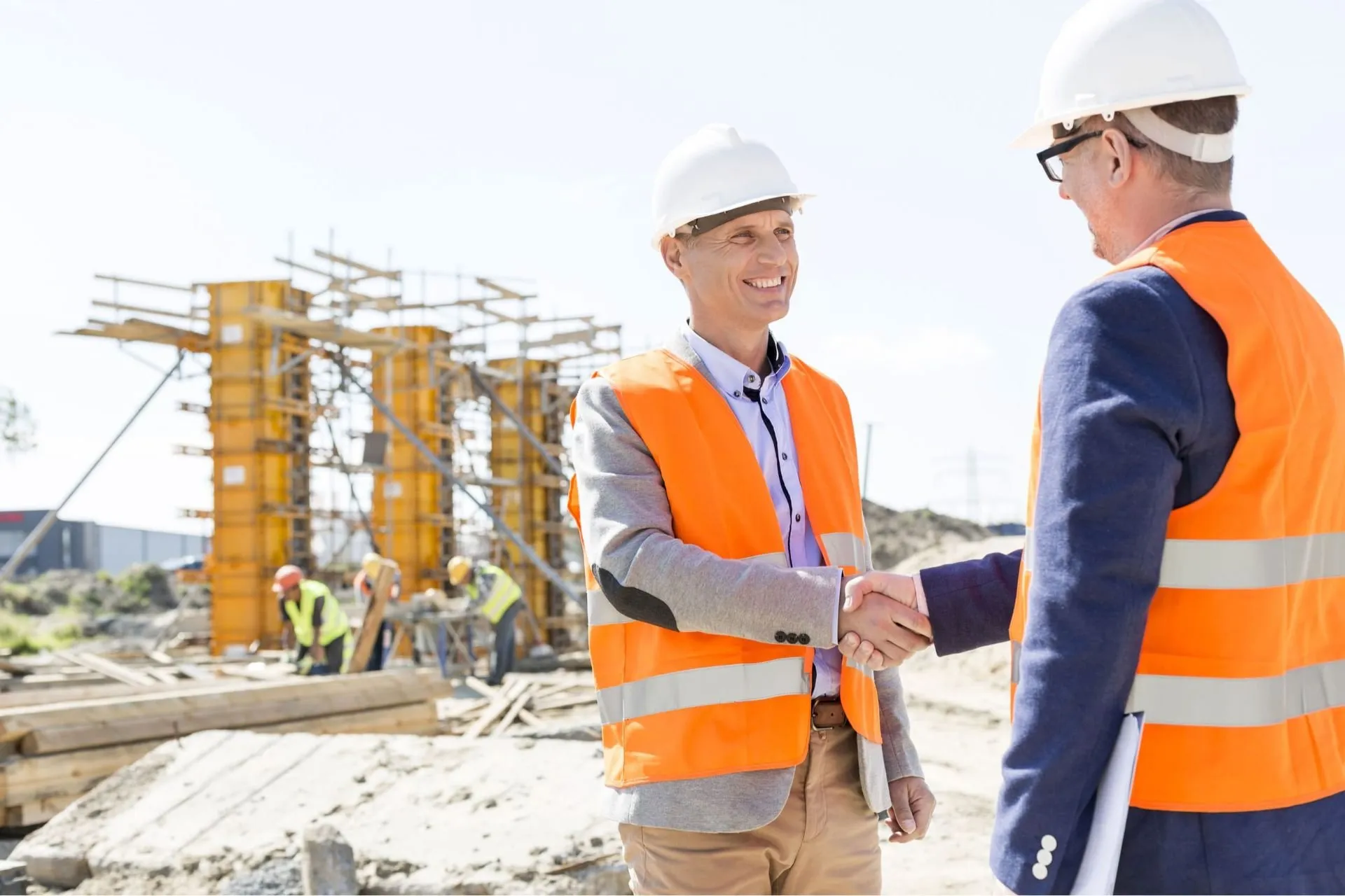 Two construction professionals shaking hands on site